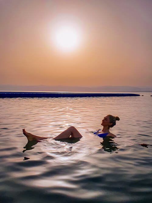 A woman floating in the Dead Sea in Jordan at sunset