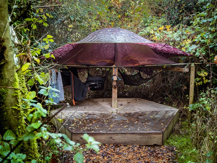 A brown suspended tent surrounded by dense forest