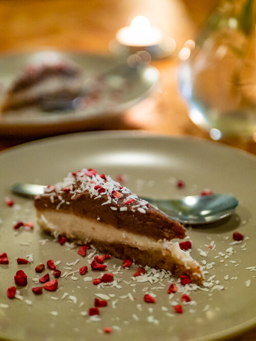 a slice of raw vegan cake with several layers and dehydrated raspberries