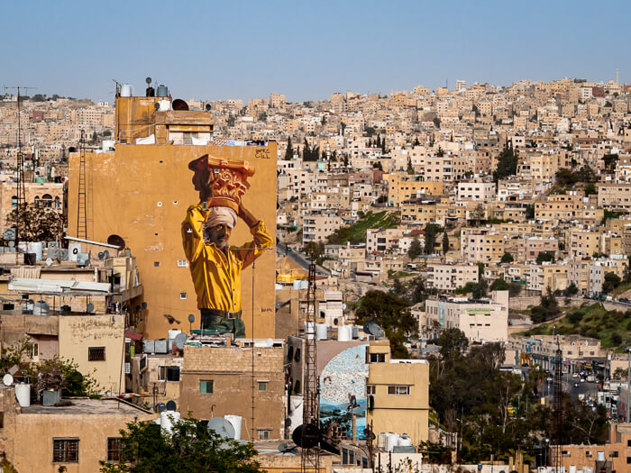 Panoramic view of Amman and its buildings, including a vibrant mural of an Arabic man