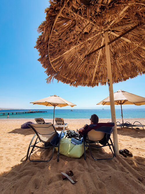 two beach chairs and an umbrella on a sandy beach in Aqaba