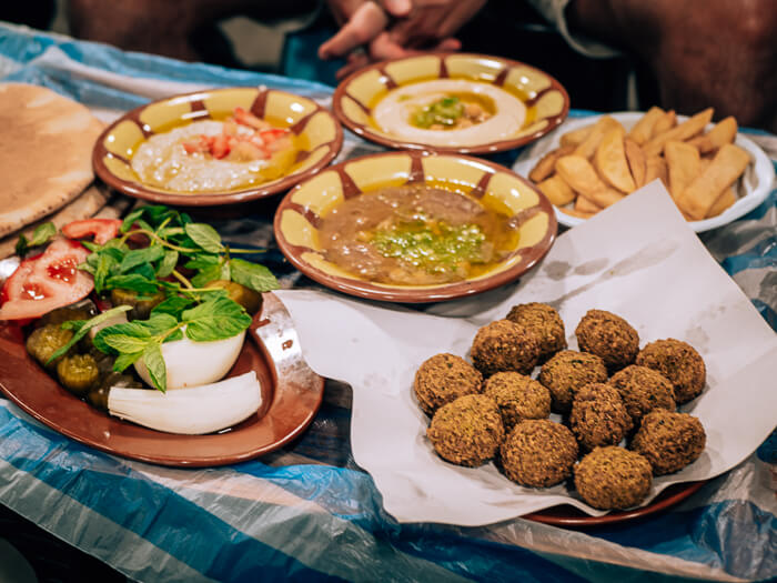 Multiple plates with Middle Eastern food such as falafels, hummus and foul mudammas at Hashem restaurant