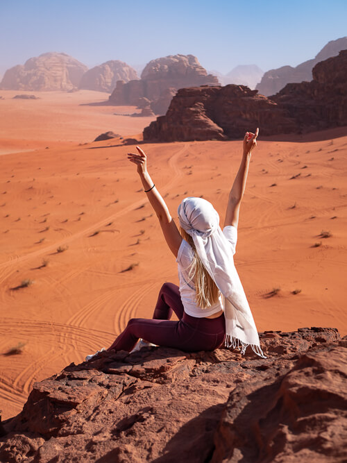 a woman sitting on a rock overlooking the Mars-like scenery of the Wadi Rum desert