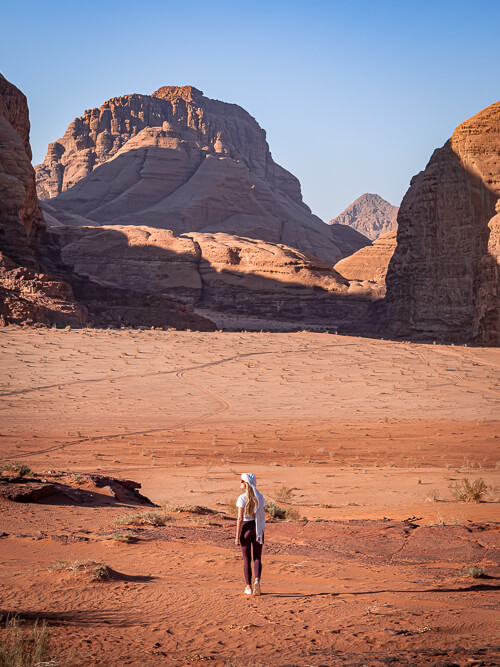 A woman hiking in Wadi Rum, surrounded by dramatic sandstone mountains
