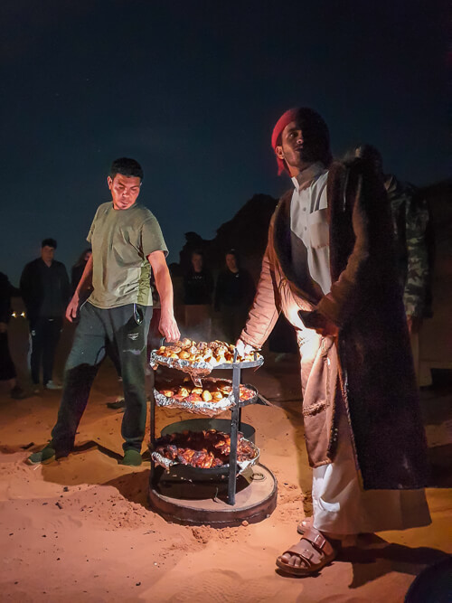 Two Bedouins showcasing a traditional dinner called Zarb which is cooked in sand