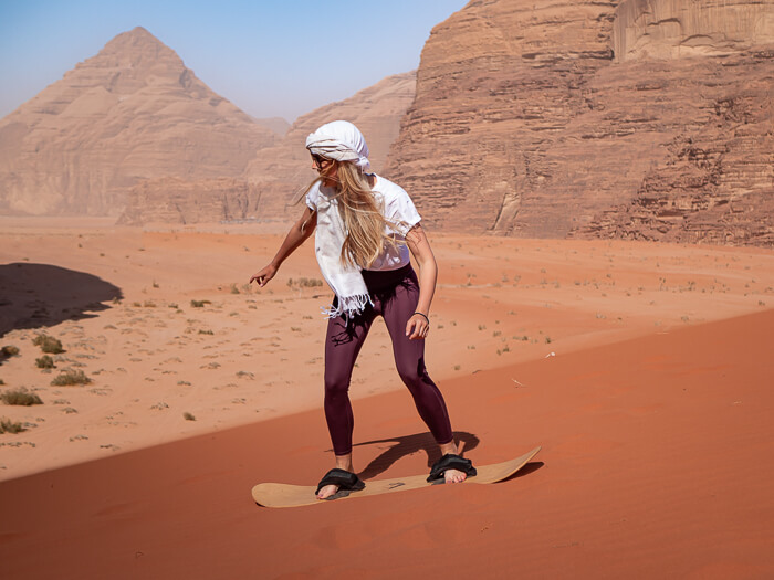 Sandboarding on a huge red sand dune, one of the top things to do in Wadi Rum, Jordan