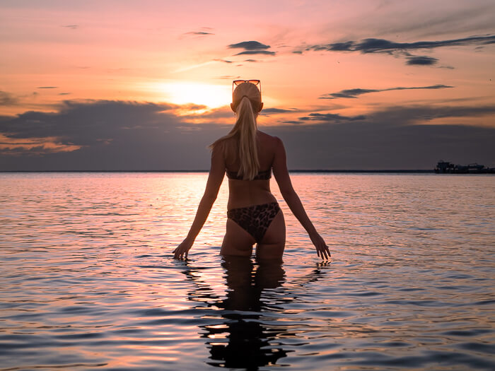 a woman standing in the calm waters of the Tapajos River during sunset