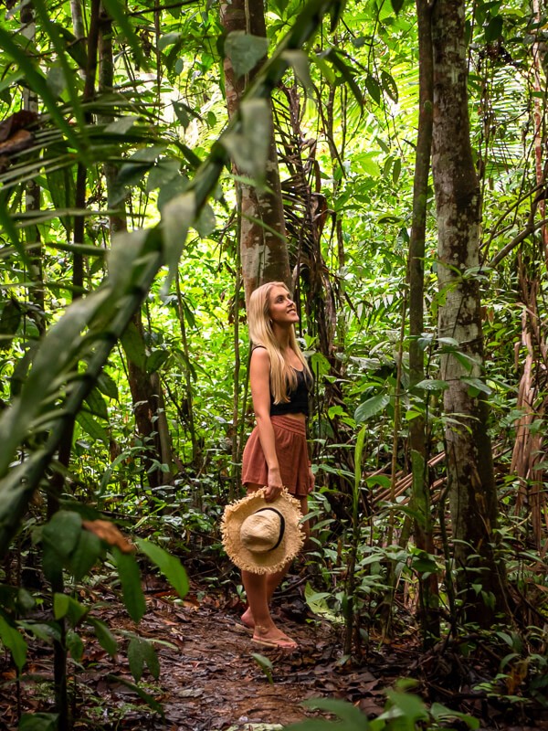 A woman standing in the middle of a lush rainforest and gazing at the treetops near Manaus, Brazil
