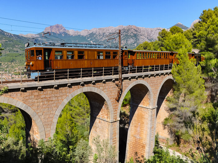 The old wooden Soller train crossing a stone bridge in northern Mallorca.