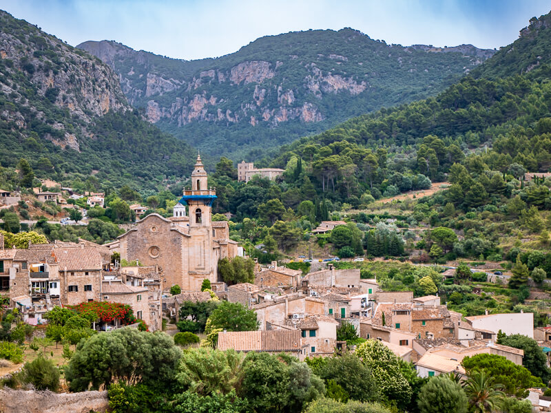 The village of Valldemossa with its traditional stone houses nestled between green mountains.