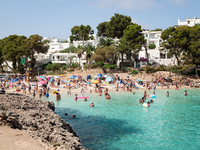 Tourists bathing in the crystalline waters of Cala Gran beach, one of the best things to do in Cala d'Or
