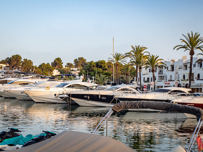 a row of white yachts docked in Cala d'Or Marina