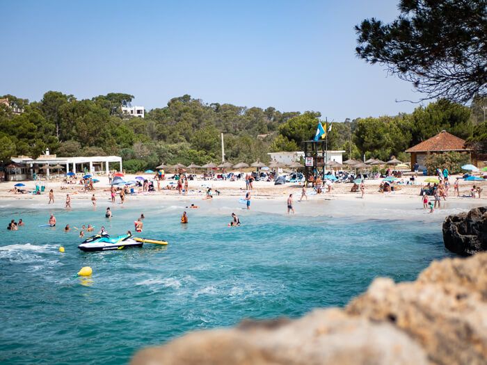 People swimming in the blue waters of Mondrago Natural Park on the south coast of Mallorca.