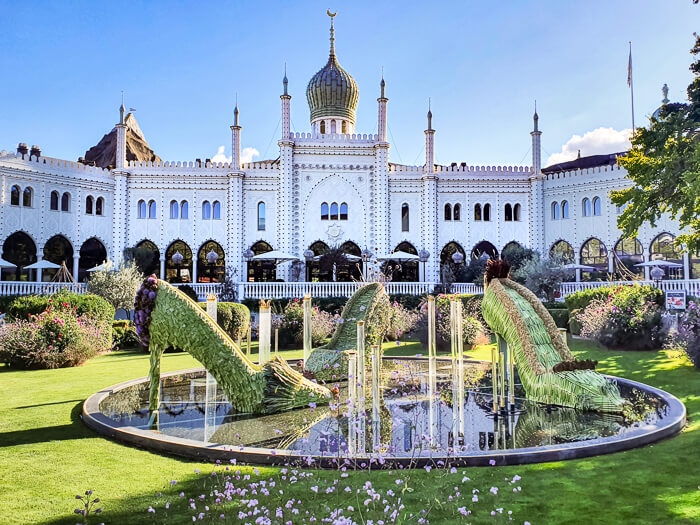 A white building with ornate facade and a fountain at Tivoli Gardens in Copenhagen