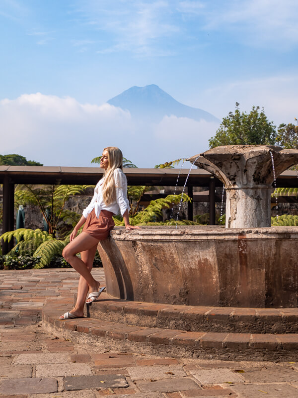 A woman leaning on an old fountain in Hotel Casa Santo Domingo in Antigua Guatemala