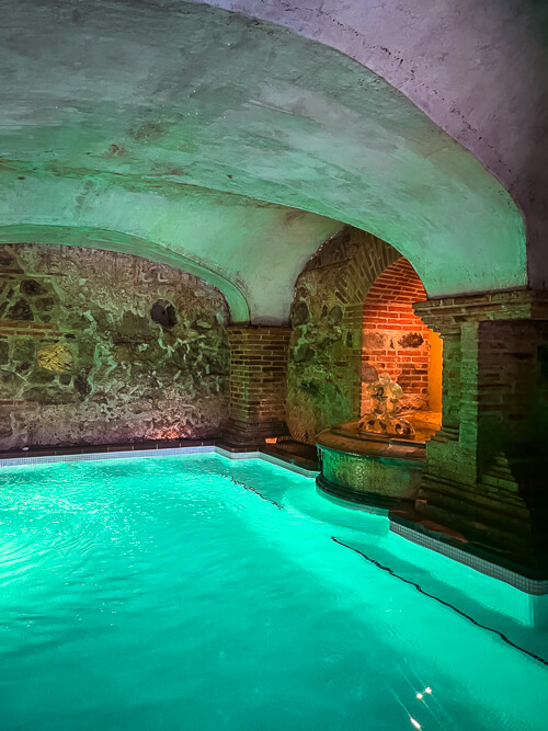 A large illuminated roman bath with a vaulted ceiling