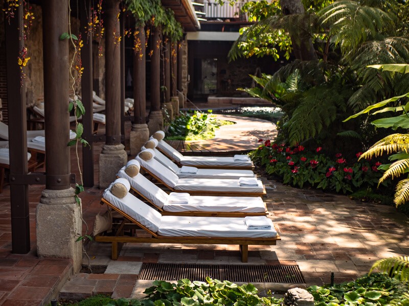 White sun loungers in a garden full of lush vegetation at Hotel Casa Santo Domingo Spa