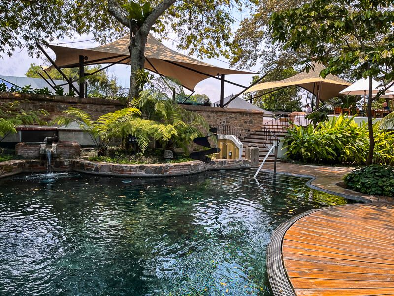 An outdoor pool surrounded by wooden decks and tropical vegetation at Hotel Spa Casa Santo Domingo