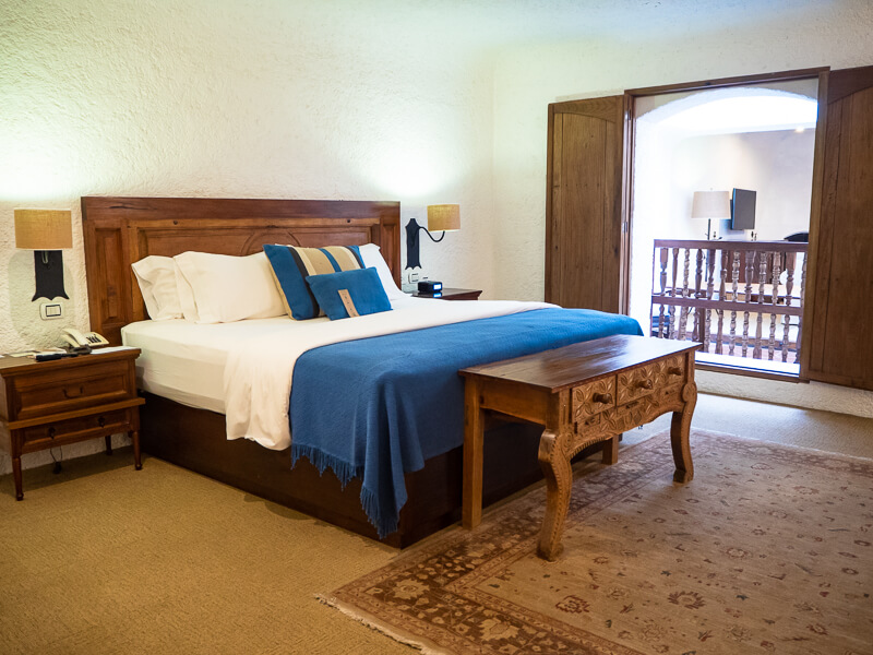 a hotel room with white walls and rustic wooden furniture
