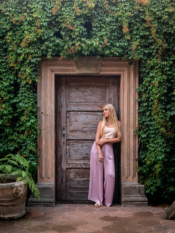 Me leaning on an old wooden doorway surrounded by greenery