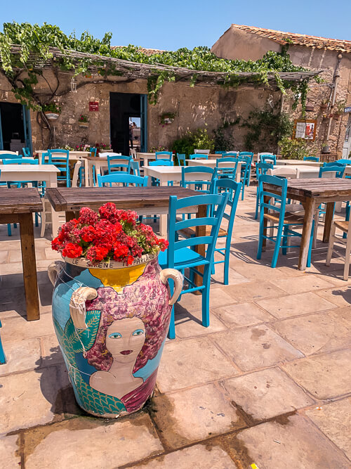 A Sicilian vase and blue chairs at a restaurant in Marzamemi, one of the most beautiful places in Sicily.