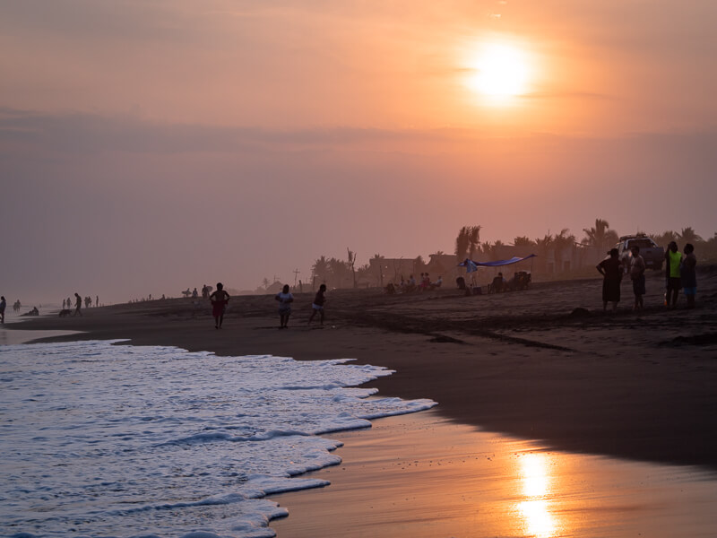 people gathering on a beach during sunset in El Paredon, one of the best Guatemala highlights for backpackers and surfers