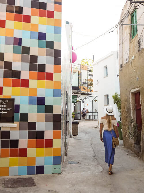 A woman walking along a colorful alleyway at Farm Cultural Park in Favara, a unique place to add to your Sicily road trip.