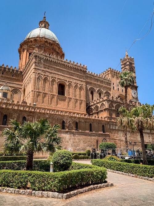 The intricate facade of Palermo Cathedral, decorated with columns and arches in Arab-Norman architectural style.