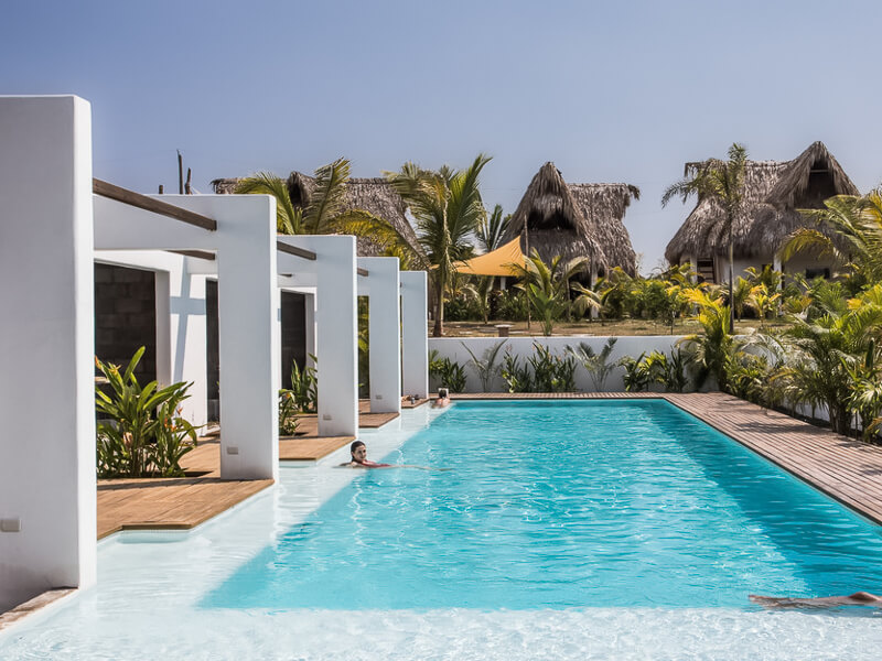 a swimming pool surrounded by a wooden deck and tropical plants at Swell Hotel, Guatemala