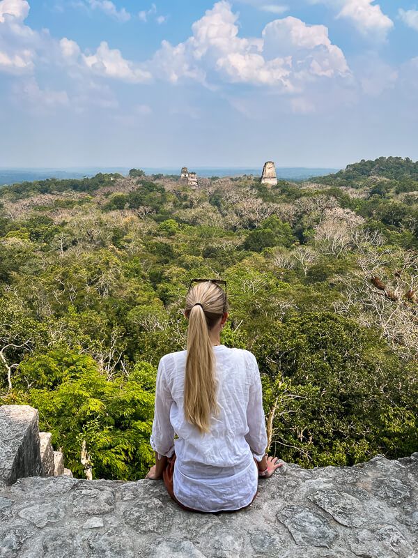 A woman admiring the view from the top of an ancient Maya temple, one of the best things to do when visiting Tikal