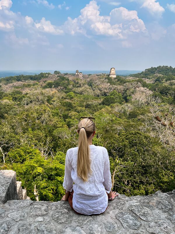 Me sitting on a rock. admiring the view from the top of an ancient Maya temple, one of the best things to do when visiting Tikal
