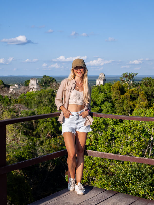 A woman standing on a viewing platform on top of a Mayan pyramid in Tikal National Park