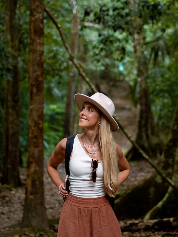 A woman walking along a trail in a rainforest in Tikal National Park