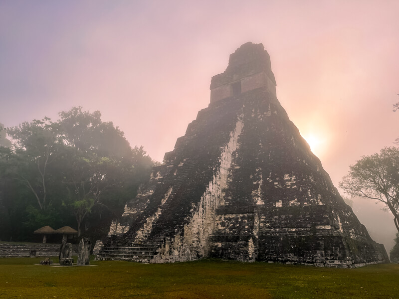 Pink hazy skies and a Mayan pyramid in the early morning in Tikal