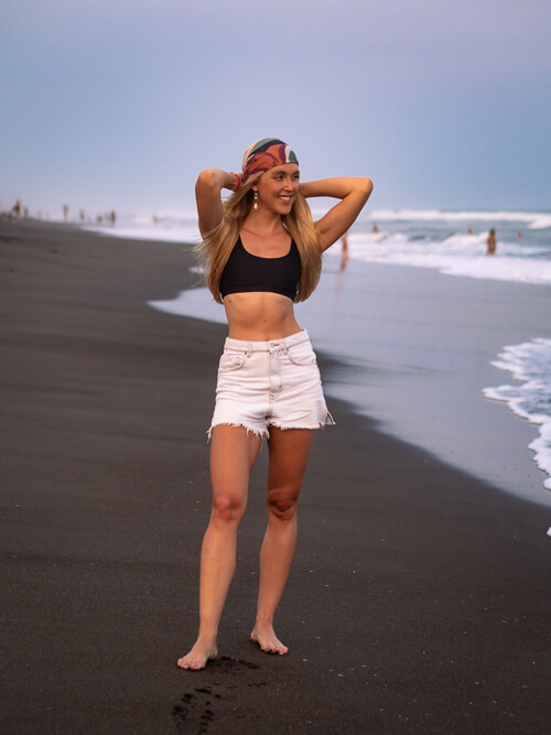 A woman standing on the black volcanic sand of Playa El Paredon beach