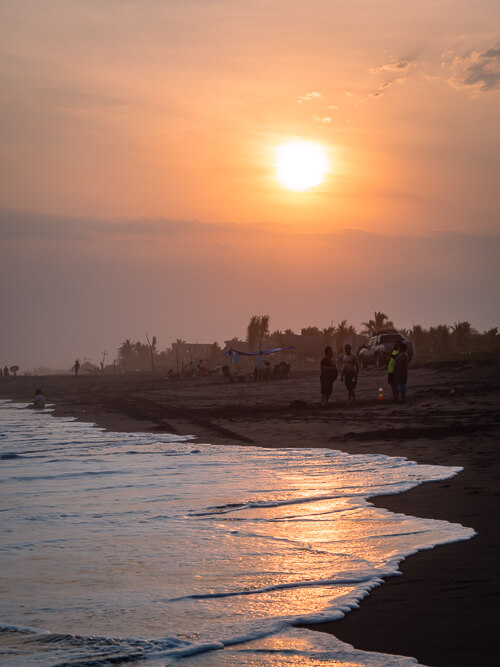 orange sunset sky and foamy waves on the popular surfing beach of El Paredon