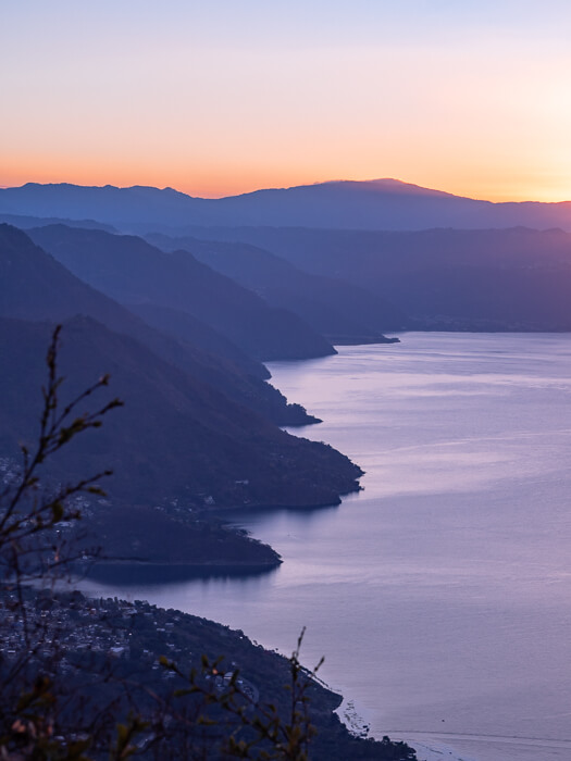 mountainous shores of Lake Atitlan against a pink sky during dawn