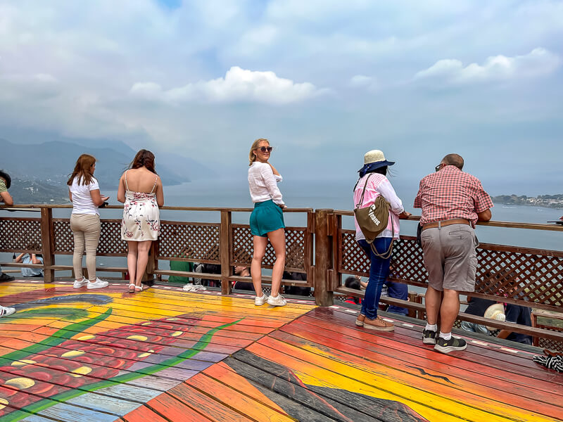 People standing on the colorfully painted Mirador Kaqasiiwaan lookout in San Juan La Laguna