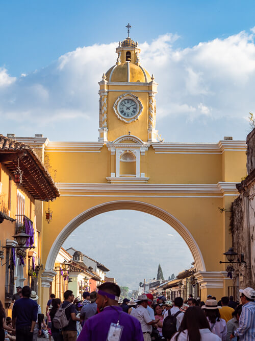 Crowds walking below the famous yellow Santa Catalina Arch in Antigua Guatemala