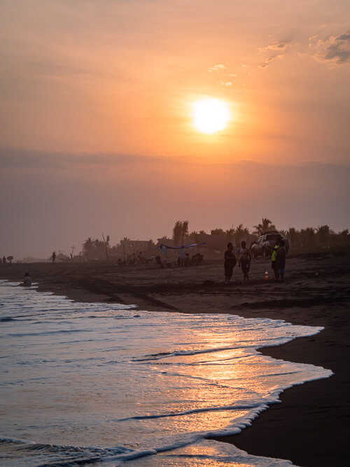 people gathering on a beach during sunset in El Paredon