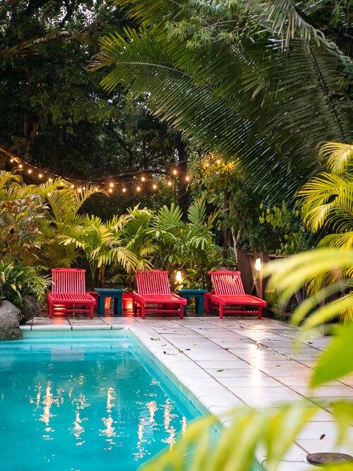 a swimming pool surrounded by red sunbeds and lush vegetation in Hotel Jungle Lodge Tikal