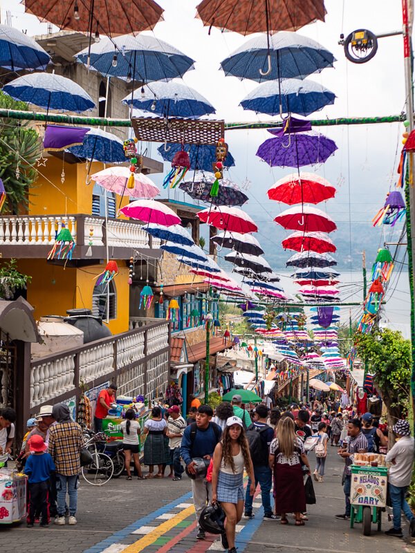 Crowds walking on a popular street decorated with colorful umbrellas in San Juan La Laguna, Guatemala