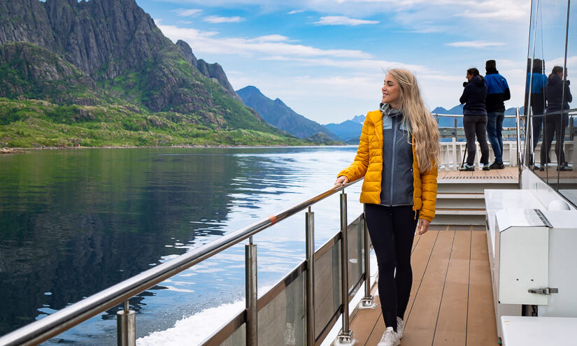 A woman in a yellow jacket standing on the deck of a ship on the Silent Trollfjord Cruise