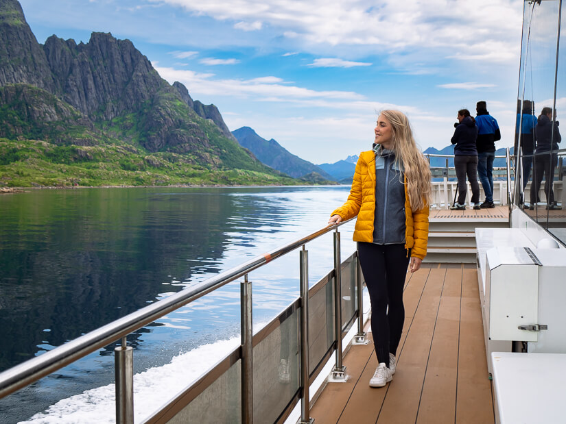 A woman in a yellow jacket standing on the deck of a ship on the Silent Trollfjord Cruise