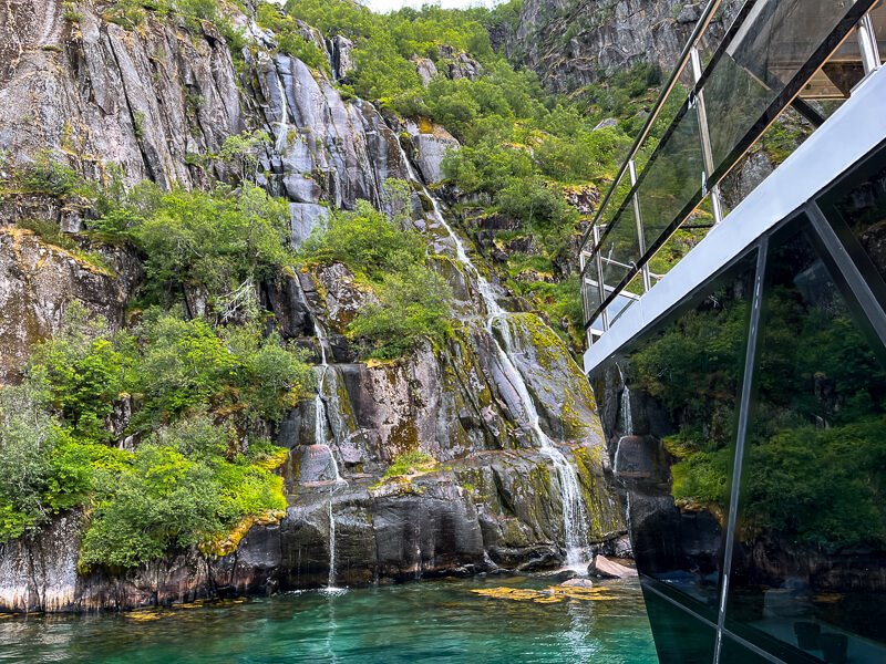 A modern electric ship approaching a small waterfall in the iconic Trollfjord, Norway 