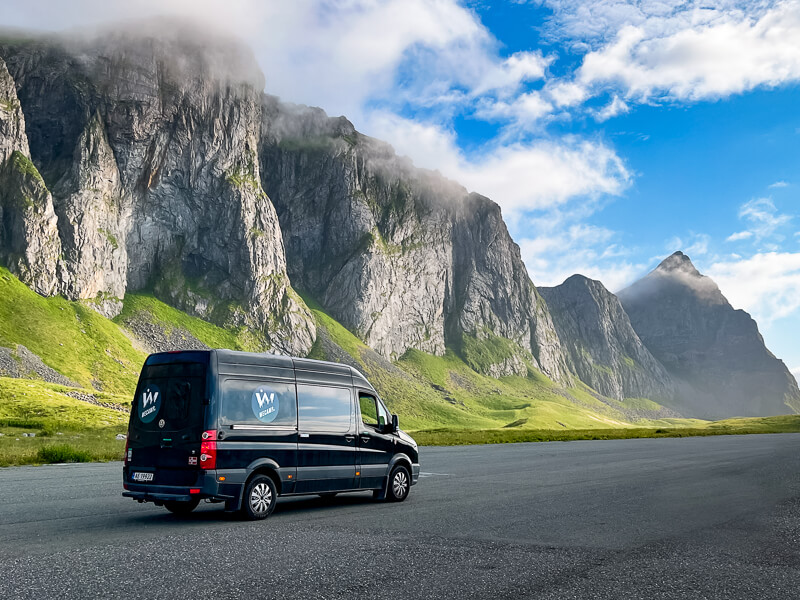 A black van surrounded by dramatic mountains on Værøy island, a great place for campervanning in Norway