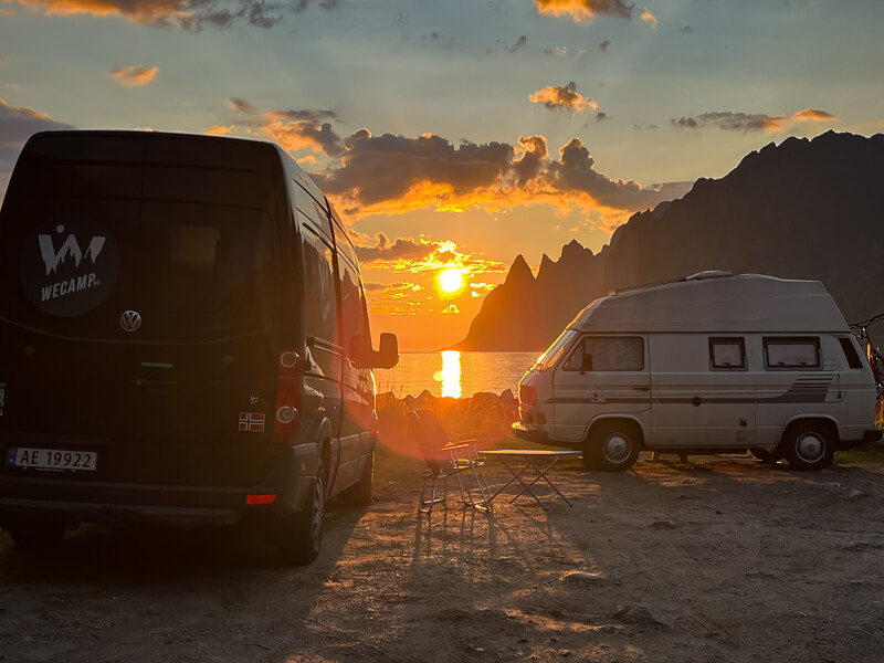 Two campervans parked at a free camping spot on Senja island with a view of the Midnight Sun