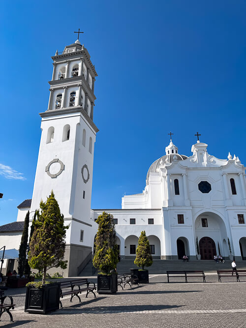 A church with a white tower against bright blue sky in Cayala neighborhood in Guatemala City