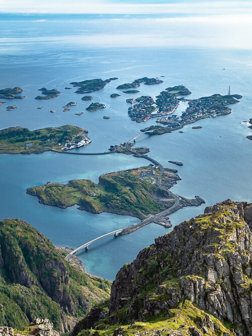 A top-down view of the Henningsvær village spread out on small rocky islands, viewed from Festvågtind peak