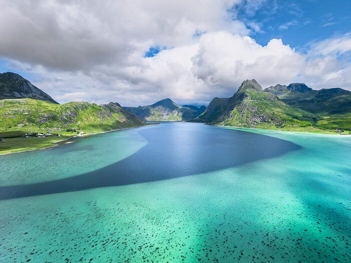A drone photo of Flakstadpollen Bay and its beautiful water in various shades of blue